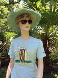 Ice Blue color crew neck tee with Hawaiian Lei design that features the initials G.V. in the center surrounded by white flowers. Global Village logo on sleeve.